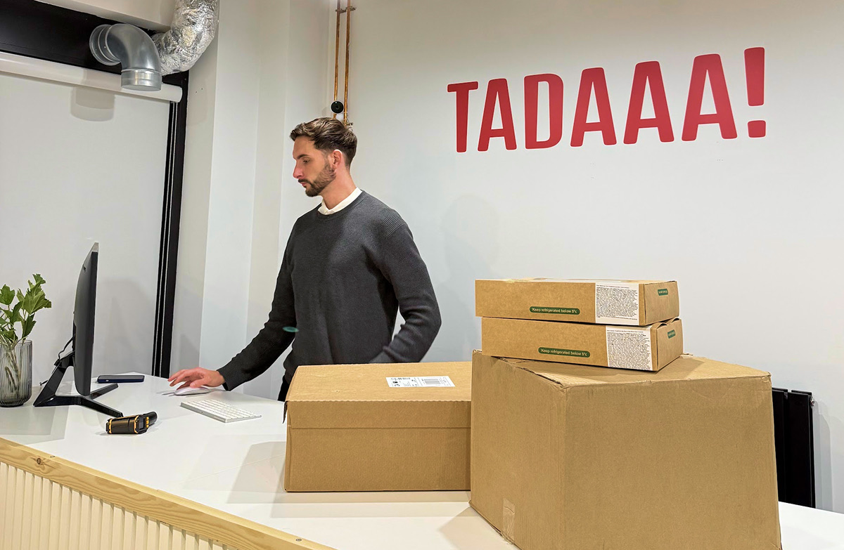 Person at desk with TADAAA! sign and packages